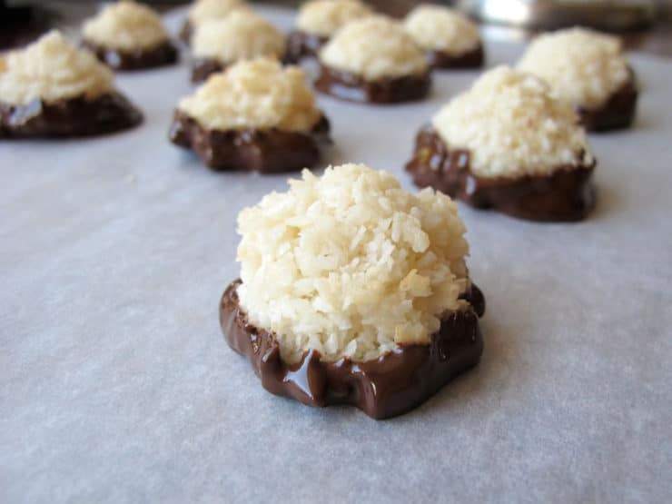 Chocolate dipped macaroons drying on wax paper.
