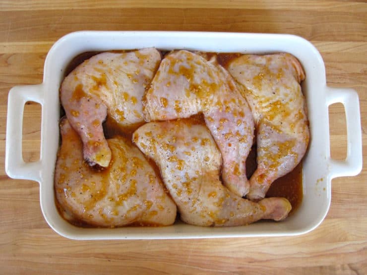 Honey garlic marinade on chicken quarters in a baking dish.