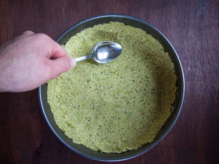 Pressing pistachio crumb crust into springform pan.