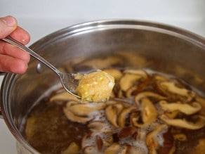 Dropping meatballs into simmering broth.
