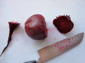 Slicing the tops and bottoms off roasted beets.