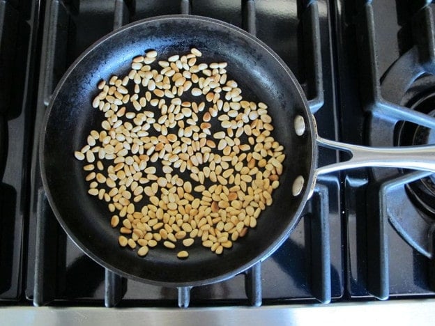 Dry toasting pine nuts in a skillet.