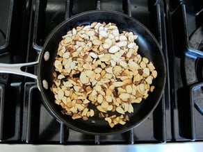 Toasting sliced almonds in a skillet.