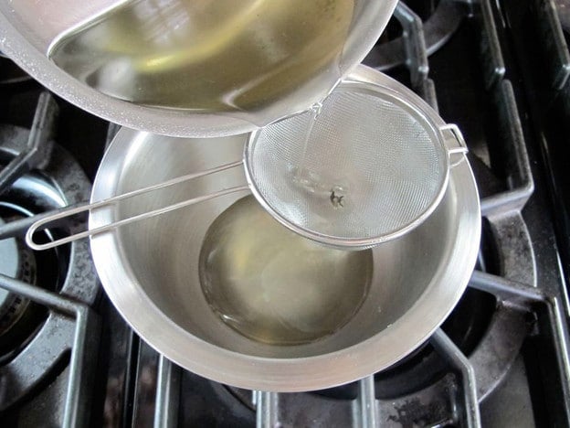 Straining rosemary from simple syrup.