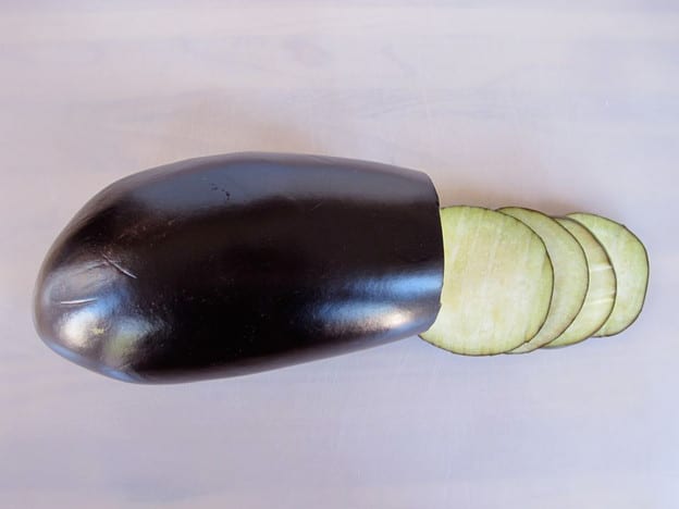 Slicing an eggplant into thin rounds.