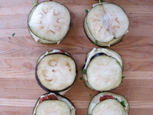 Stacking layers of eggplant rounds.