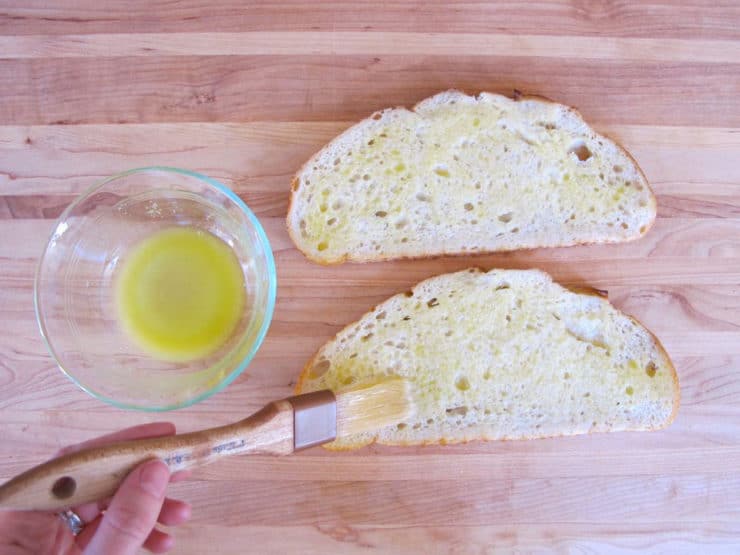 Brushing melted butter on sourdough slices.