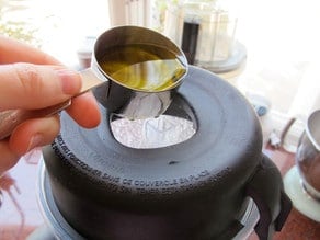 Drizzling oil into a running blender.