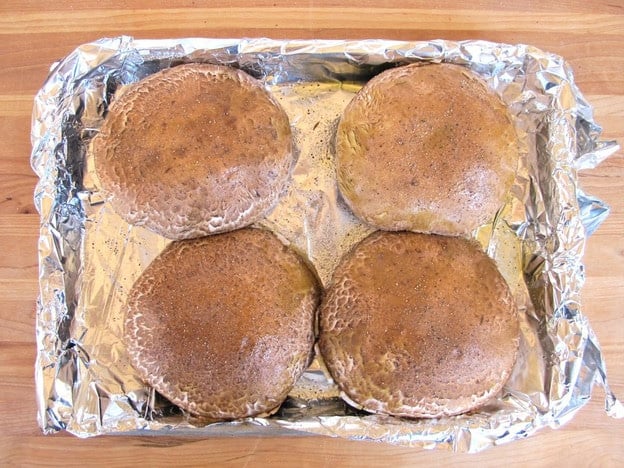 Mushroom caps on a foil-lined baking sheet.
