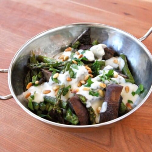 Roasted Portobellos & Asparagus with Goat Cheese Sauce serve on a stainless bowl on top of a wooden table