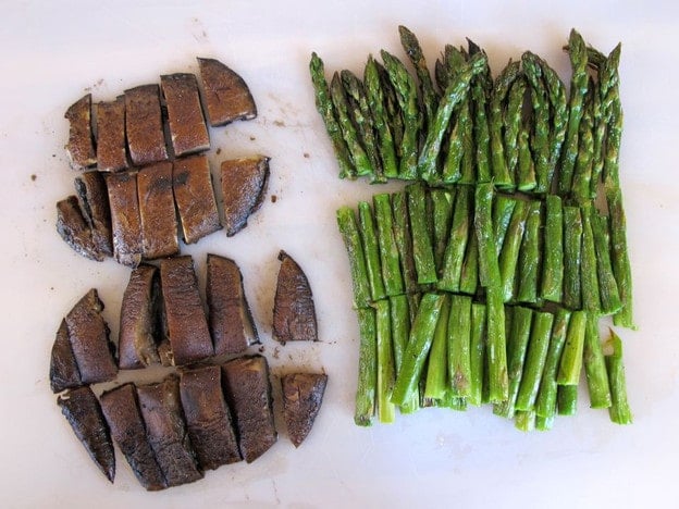 Sliced asparagus and mushrooms on a cutting board.
