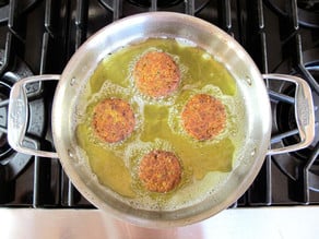 Frying chickpea patties in a skillet.
