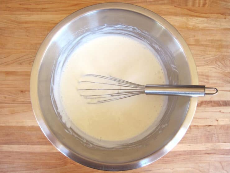 Whisking milk into yogurt in a mixing bowl.