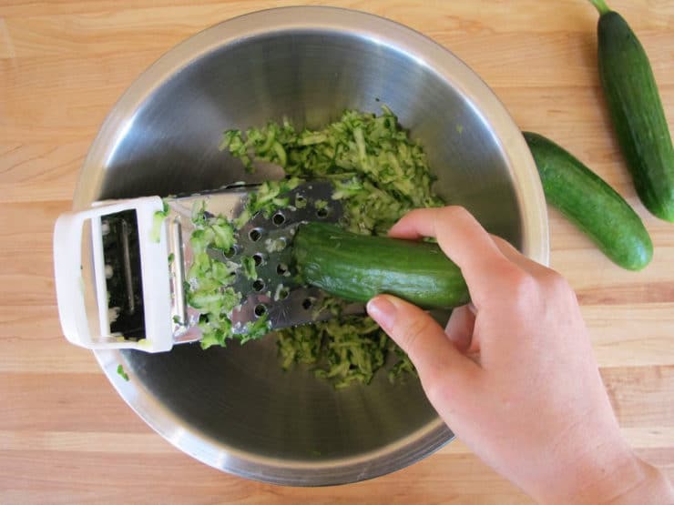 Grating cucumber into a bowl.