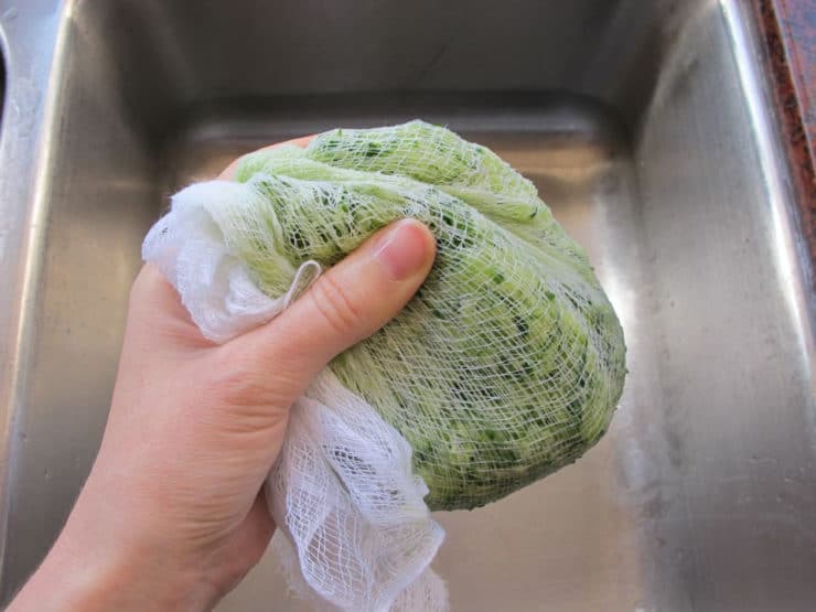 Squeezing moisture out of shredded cucumber.