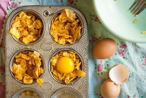 Breaking eggs into cornflake nests in a muffin tin.