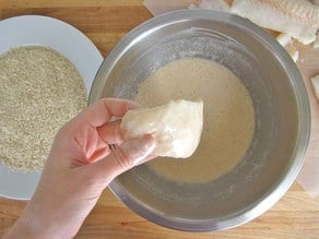 A hand dipping a fish on a batter mix for Crispy Panko Fish
