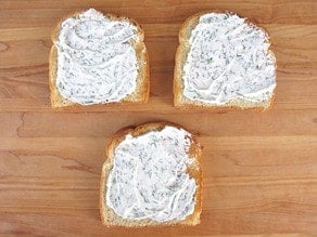 Herbed cream cheese spread on three slices of toast.