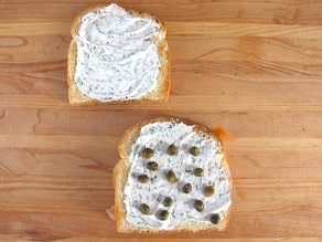 Capers on cream cheese on a slice of toast.