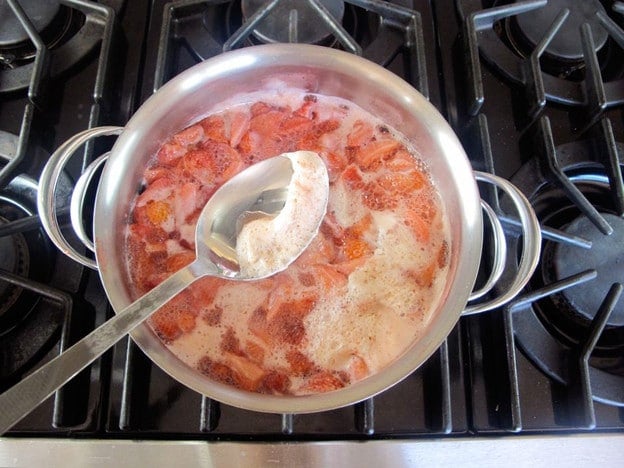Skimming foam off boiling strawberries.