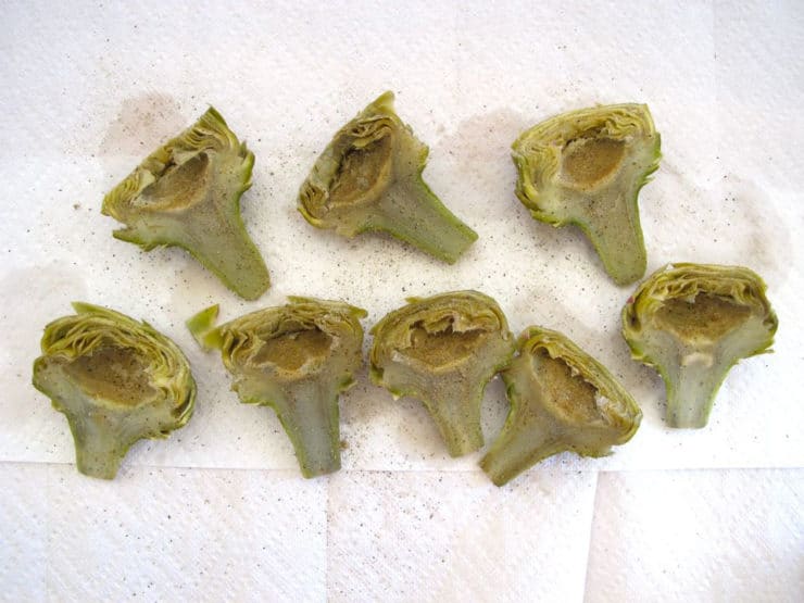 Blanched artichoke hearts drying on a towel.