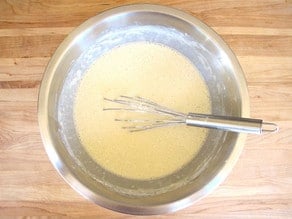 Flour whisked into milk in a mixing bowl.