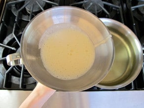 Batter in a funnel with finger over the opening.