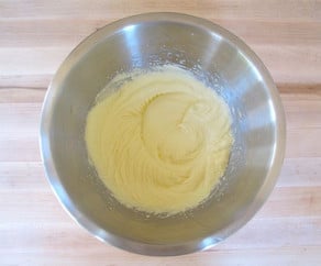 Butter, sugar, and eggs beat together in a mixing bowl.