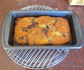 Cooked marble cake in a loaf pan cooling on a rack.