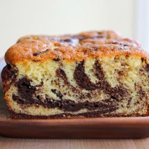 Baked marble cake sliced on wooden tray.