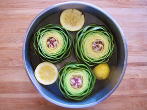 Artichokes in a pot of water with lemons.