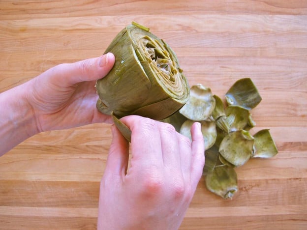 Removing cooked leaves from an artichoke.