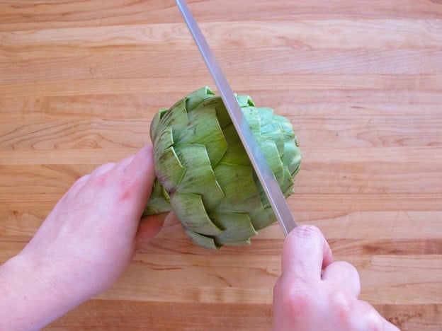 Slicing the top off an artichoke.