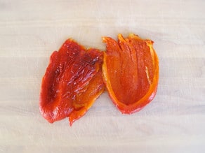 Roasted red peppers on a cutting board.