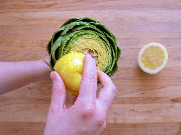 Rubbing a cut artichoke with lemon.