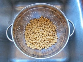 Rinsing chickpeas in a strainer.