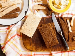 Rye bread on a cutting board with a knife.