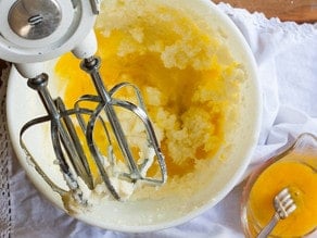 Adding wet ingredients to creamed butter.