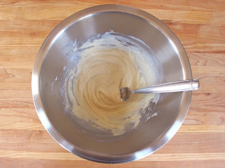 Stirring yogurt into protein powder in a mixing bowl.