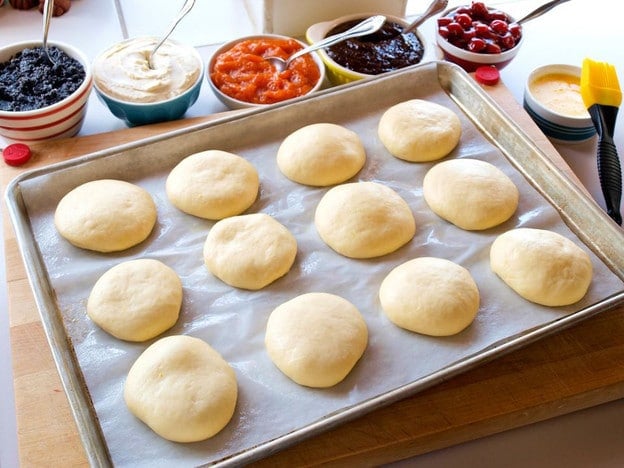 Kolaches on a lined baking sheet.