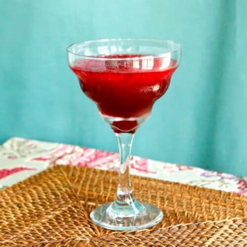 Persian Pomegranate Mocktail served on a fancy glass on top of a bamboo weaved table mat