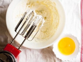 Beating butter and sugar with a hand mixer.