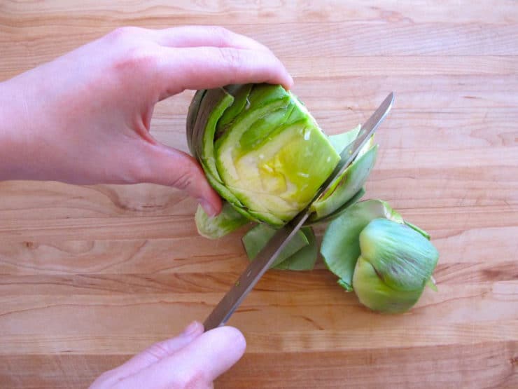 Using a knife to remove inner leaves of artichoke.