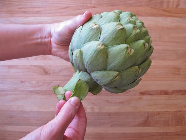 Peeling outer leaves of an artichoke.