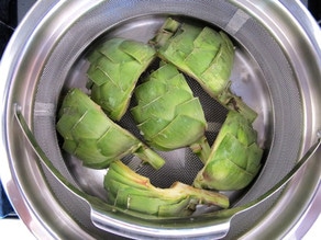 Steaming artichoke halves in a pot.