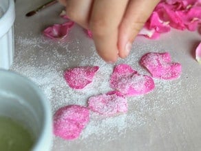 Sprinkling sugar over rose petals.