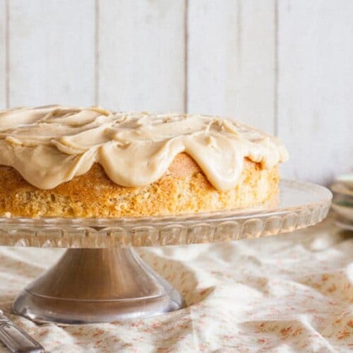 Cider Cake with Caramel Frosting served on a cake holder stand with bright background and a knife on the side