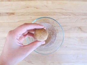 Rolling cookie dough balls in cinnamon sugar.