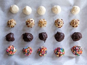 Coated bon bons chilling on a lined baking sheet.
