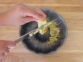 Cutting corn off the ear using a bundt pan.